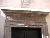 Parte superiore del portale in pietra su cui si legge una scritta in latino che riporta la data della edificazione della chiesa