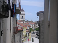 Una strada, con sullo sfondo il campanile della chiesa Madre di Santa Maria delle Grazie