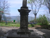 La base della croce all'ingresso del paese, in un giardinetto