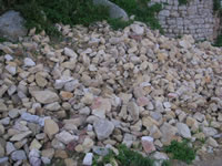 Le pietre cadute alla base di una torre cilindrica del Castello di Monteverde