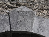 Particolare di un portale in pietra, su cui si legge con estrema difficoltà la data del 1716