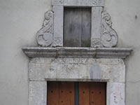 Particolare della parte superiore del portale in pietra laterale della chiesa madre di Santa Paolina
